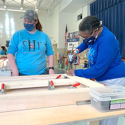 Langley team member Jennifer Walker drills a hole while building a bunk bed at a project with Sleep In Heavenly Peace.